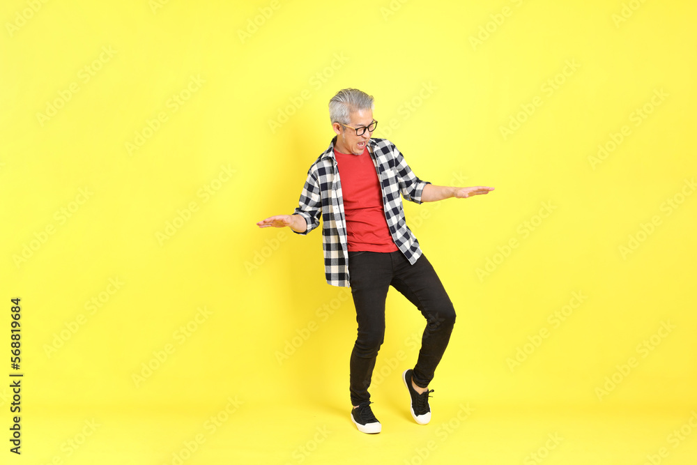The 40s adult Asian man with casual dressed standing on the yellow background. The 40s adult Asian man with casual dressed standing on the yellow background.