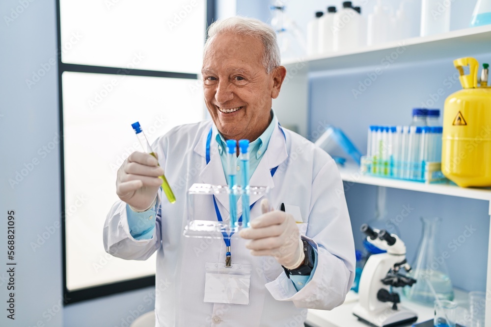 Senior man wearing scientist uniform holding test tubes at laboratory Senior man wearing scientist uniform holding test tubes at laboratory
