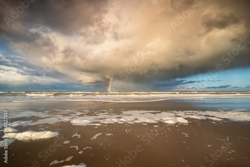 dramatic storm cloud and rainbow on sea shore photo