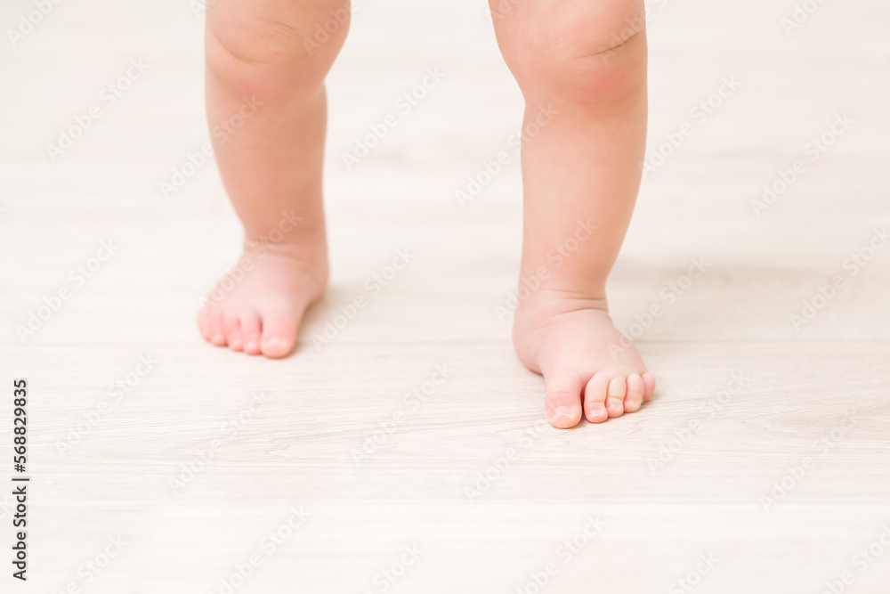 Baby barefoot on light wooden floor background. Closeup. First steps. Front view. Baby barefoot on light wooden floor background. Closeup. First steps. Front view.