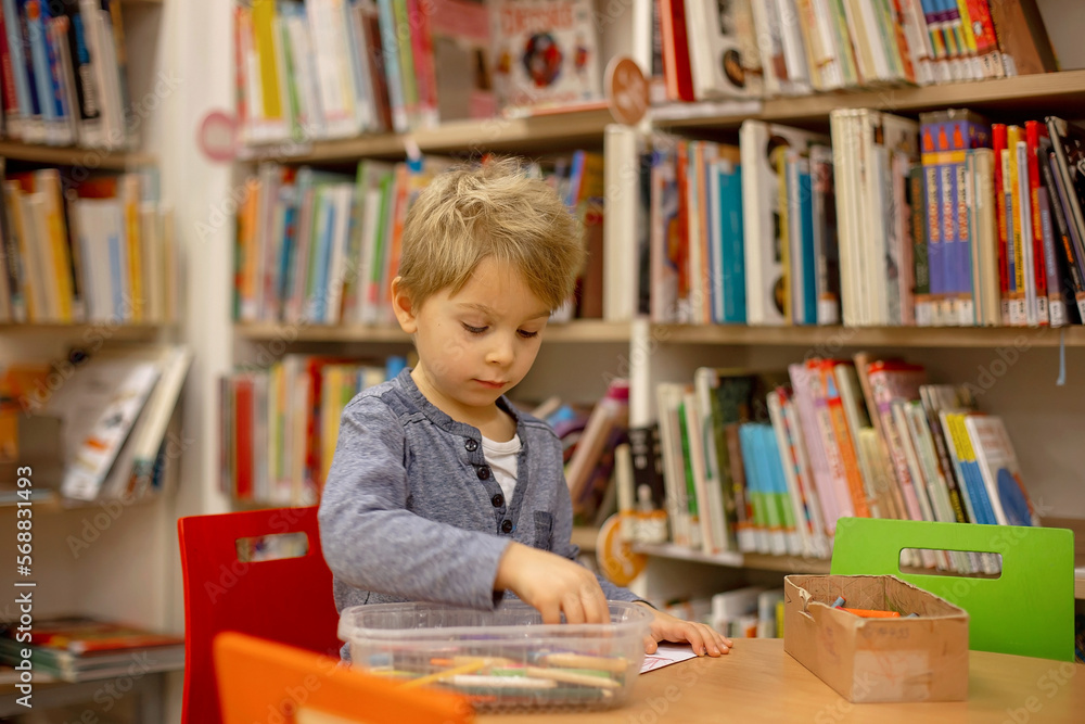 Adorable little boy, sitting in library, reading book and choosing what to lend, kid in book store. Adorable little boy, sitting in library, reading book and choosing what to lend, kid in book store.