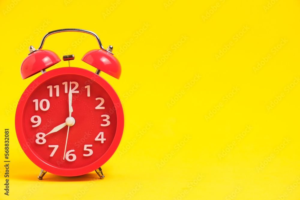 Red alarm clock yellow background showing eight morning.