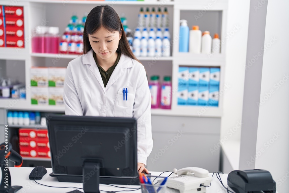 Chinese woman pharmacist using computer working at pharmacy
