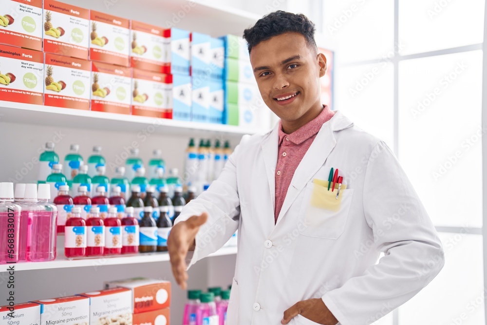 Young latin man pharmacist smiling confident shake hand at pharmacy