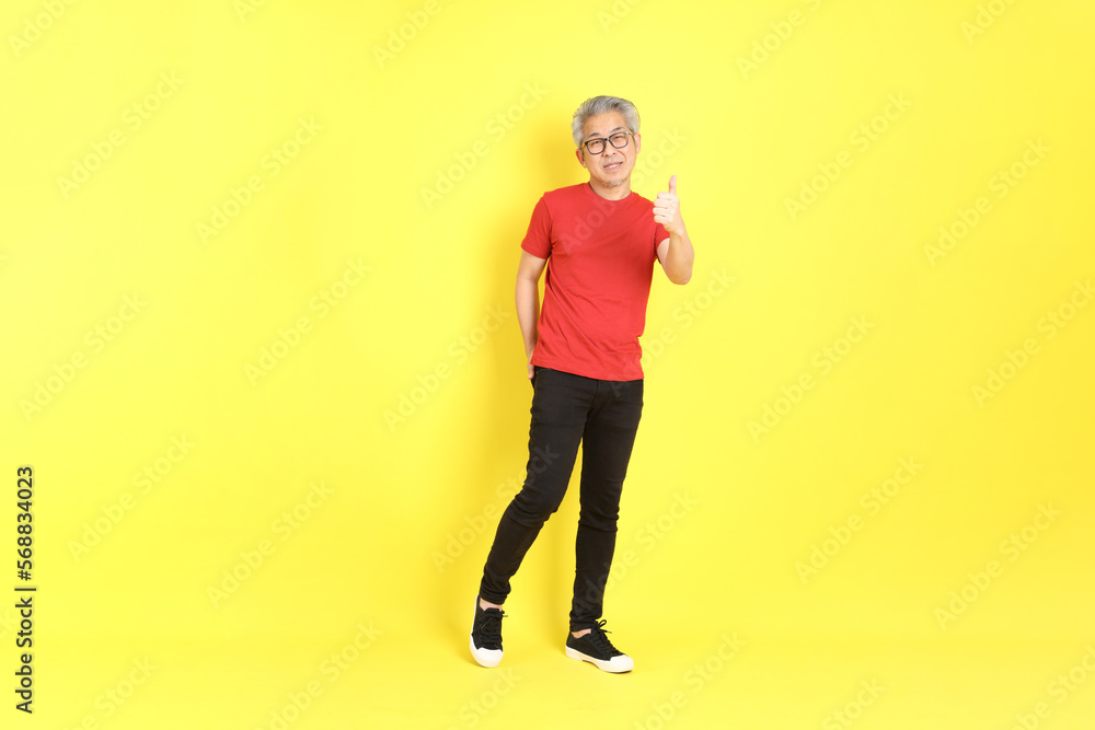 The 40s adult Asian man with casual dressed standing on the yellow background. The 40s adult Asian man with casual dressed standing on the yellow background.