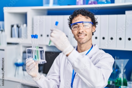 Young hispanic man scientist holding test tubes at laboratory