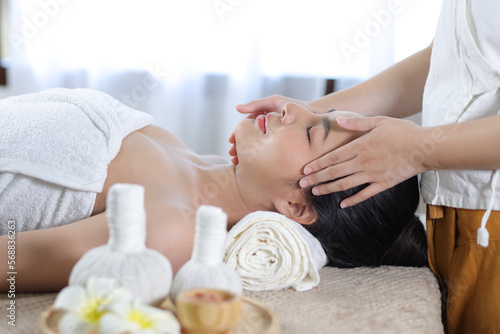 Relaxed Asian woman receiving beauty massage in spa salon.
