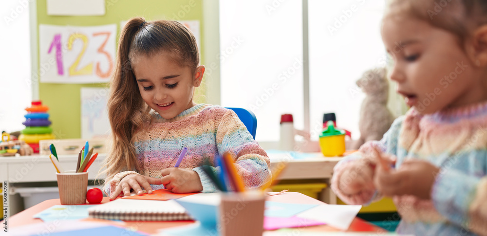 Fototapeta premium Two kids preschool students sitting on table drawing on paper at kindergarten
