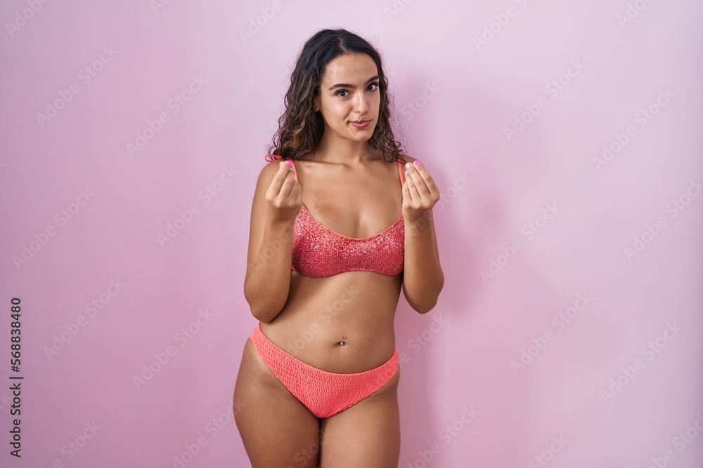Young hispanic woman wearing lingerie over pink background doing money gesture with hands, asking for salary payment, millionaire business Young hispanic woman wearing lingerie over pink background doing money gesture with hands, asking for salary payment, millionaire business