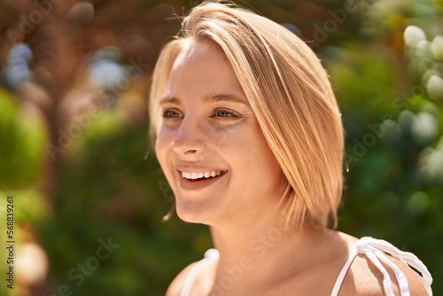 Young blonde woman smiling confident looking to the side at park