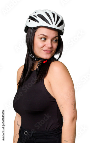 Young caucasian woman wearing a helemet isolated looks aside smiling, cheerful and pleasant. © Asier