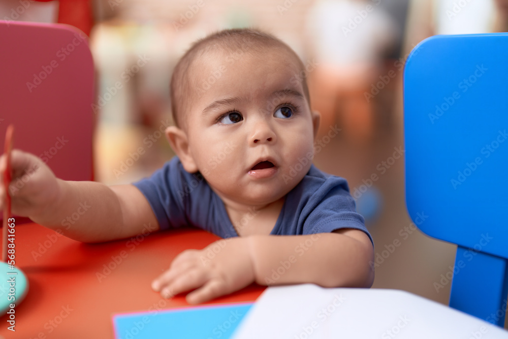 Adorable chinese toddler leaning on table standing at kindergarten Adorable chinese toddler leaning on table standing at kindergarten