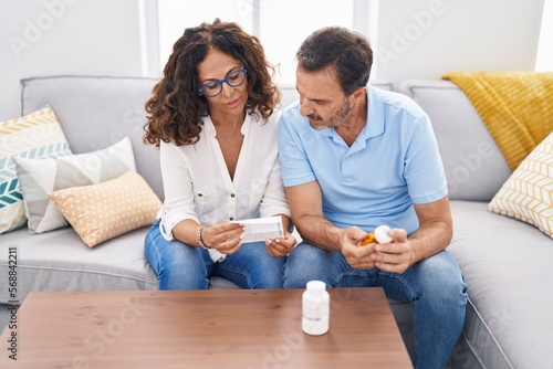 Man and woman couple holding pills reading prescription at home