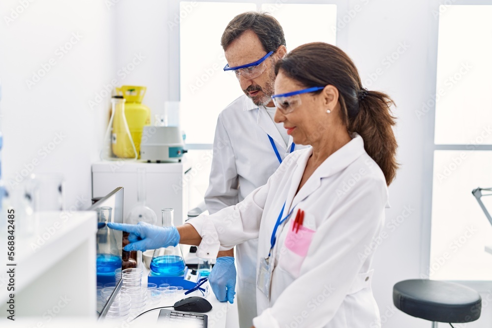 Middle age man and woman partners wearing scientist uniform working at laboratory Middle age man and woman partners wearing scientist uniform working at laboratory
