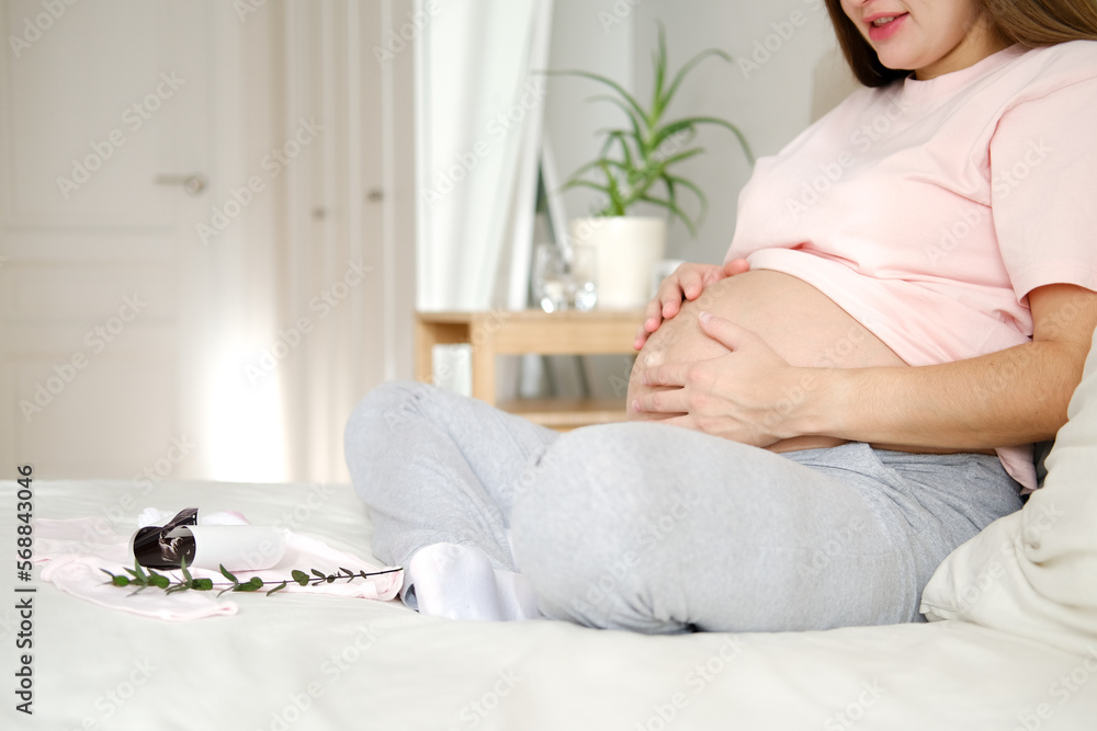 Young pregnant woman in home clothes strokes her big belly Young pregnant woman in home clothes strokes her big belly