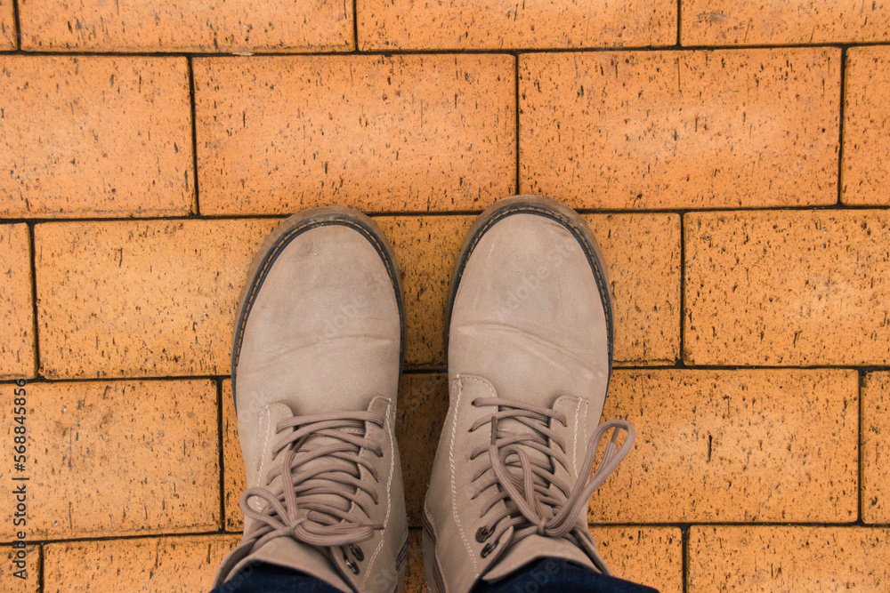 Gray women's shoes on feet and brown paving stones on background. Gray women's shoes on feet and brown paving stones on background.