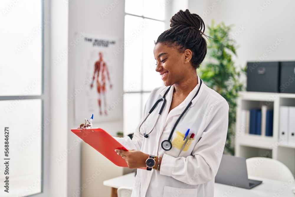 African american woman wearing doctor uniform writing on document at clinic African american woman wearing doctor uniform writing on document at clinic