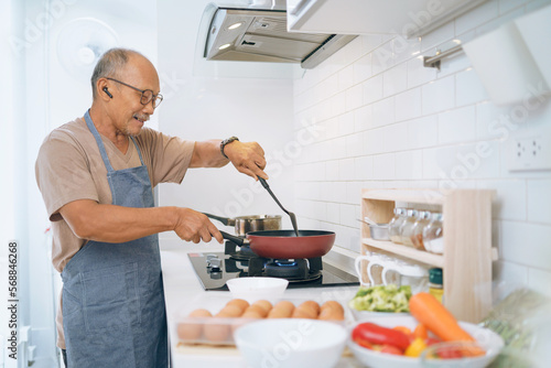 Happy Asian Mature adult man wearing eyeglasses cooking in kitchen, Prepare Food.