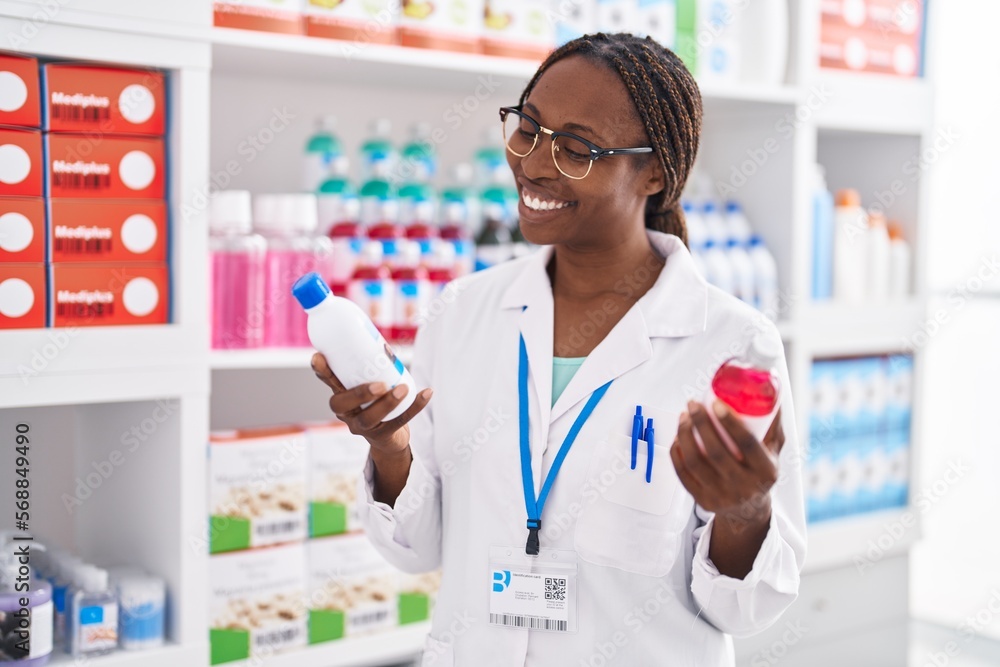 African american woman pharmacist smiling confident holding medication bottles at pharmacy African american woman pharmacist smiling confident holding medication bottles at pharmacy