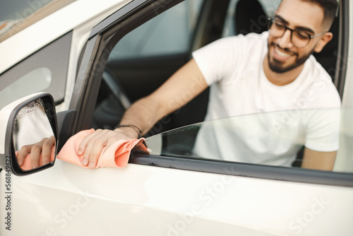 Indian man polishing inside his white car with a rug