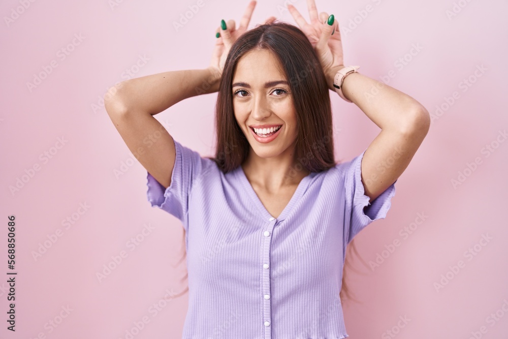 Young hispanic woman with long hair standing over pink background posing funny and crazy with fingers on head as bunny ears, smiling cheerful Young hispanic woman with long hair standing over pink background posing funny and crazy with fingers on head as bunny ears, smiling cheerful
