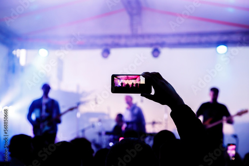 People on the dance floor are shooting a concert on a mobile phone.