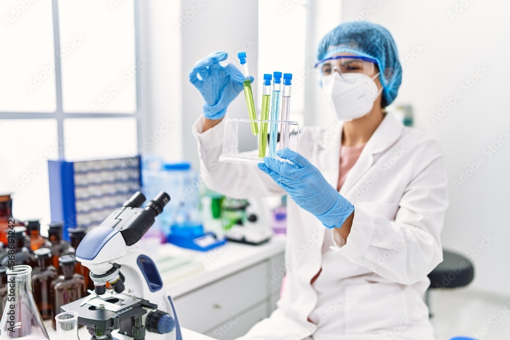 Young latin woman wearing scientist uniform holding test tube at laboratory Young latin woman wearing scientist uniform holding test tube at laboratory