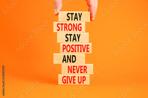Never give up symbol. Concept words Stay strong stay positive never give up on wooden blocks. Beautiful orange background. Copy space. Businessman hand. Motivational business never give up concept.