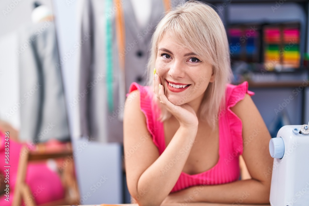 Young blonde woman tailor smiling confident sitting on table at gaming room