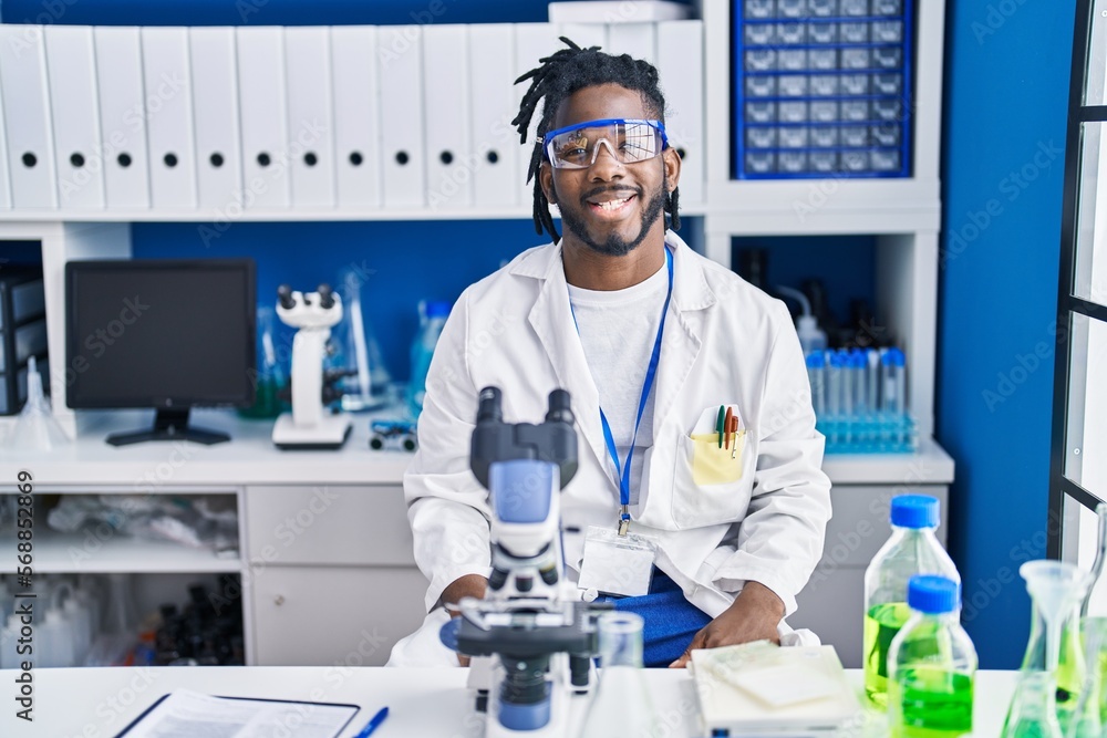 African man with dreadlocks working at scientist laboratory with a happy and cool smile on face. lucky person. African man with dreadlocks working at scientist laboratory with a happy and cool smile on face. lucky person.
