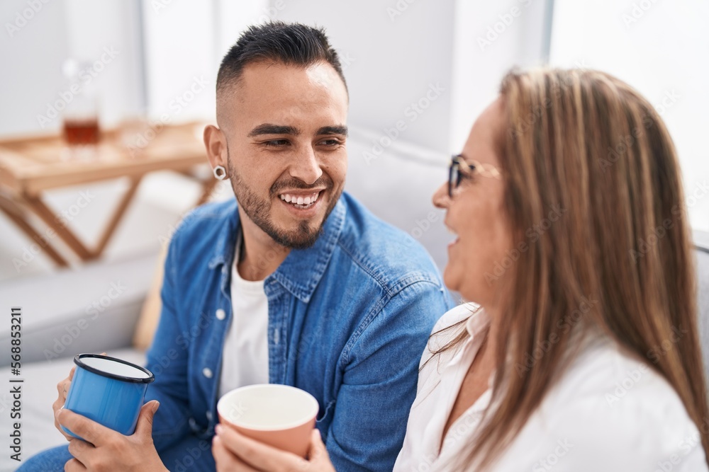 Man and woman mother and son drinking coffee sitting on sofa at home Man and woman mother and son drinking coffee sitting on sofa at home