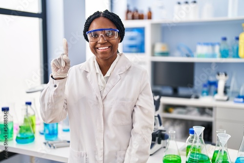 African american woman working at scientist laboratory smiling with an idea or question pointing finger up with happy face, number one photo