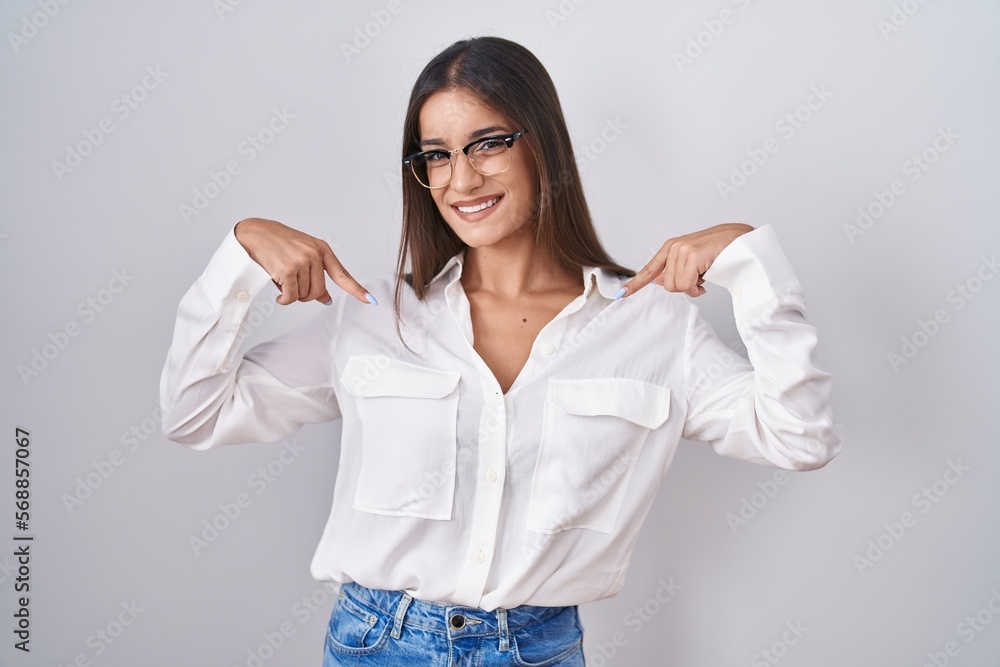 Young brunette woman wearing glasses looking confident with smile on face, pointing oneself with fingers proud and happy. Young brunette woman wearing glasses looking confident with smile on face, pointing oneself with fingers proud and happy.