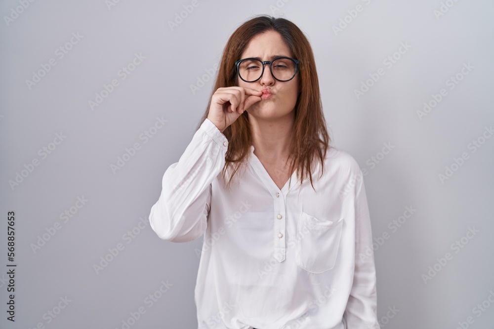 Brunette woman standing over white isolated background mouth and lips shut as zip with fingers. secret and silent, taboo talking Brunette woman standing over white isolated background mouth and lips shut as zip with fingers. secret and silent, taboo talking