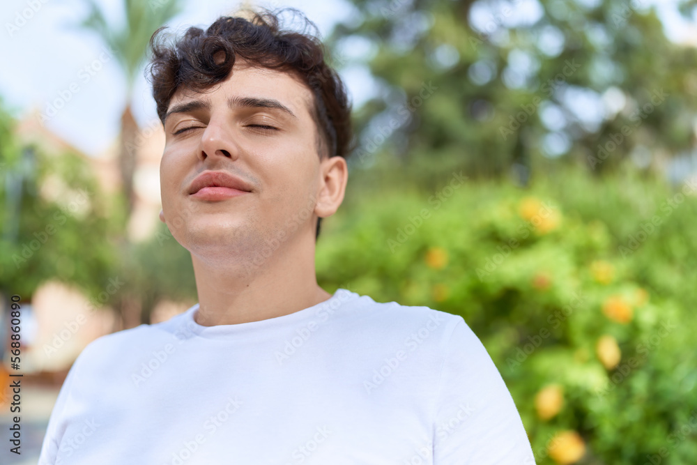 Non binary man breathing with closed eyes at park Non binary man breathing with closed eyes at park