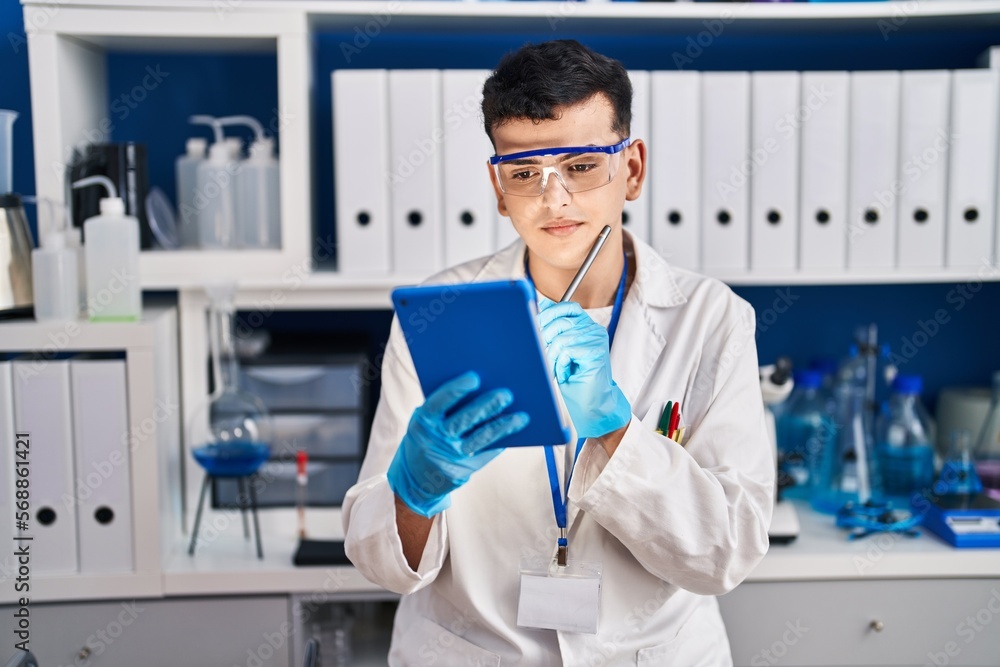 Young non binary man scientist write on touchpad at laboratory Young non binary man scientist write on touchpad at laboratory