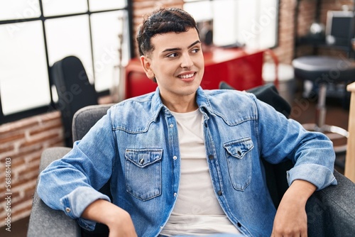 Young non binary man musician smiling confident sitting on chair at music studio
