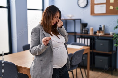 Young pregnant woman business worker stressed standing at office