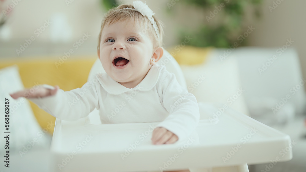 Adorable blonde baby smiling confident sitting on highchair at home Adorable blonde baby smiling confident sitting on highchair at home