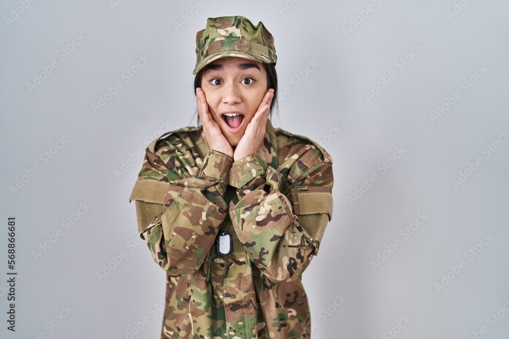 Young south asian woman wearing camouflage army uniform afraid and shocked, surprise and amazed expression with hands on face Young south asian woman wearing camouflage army uniform afraid and shocked, surprise and amazed expression with hands on face