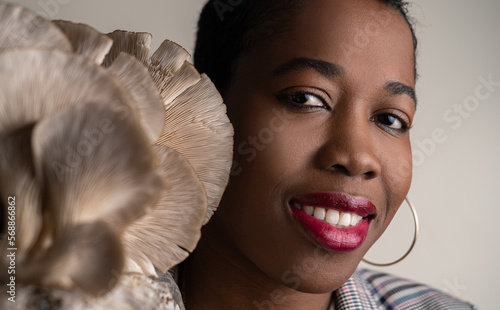 Beautiful dark skined adult woman with oyster mushroom near the face. natural colors photo