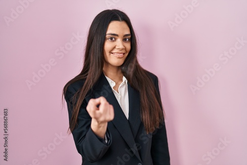 Young brunette woman wearing business style over pink background beckoning come here gesture with hand inviting welcoming happy and smiling