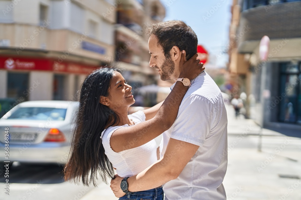 Man and woman interracial couple hugging each other at street Man and woman interracial couple hugging each other at street