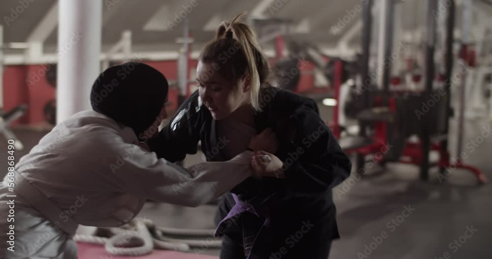 Female wrestlers clinching near exercise machine Female wrestlers clinching near exercise machine
