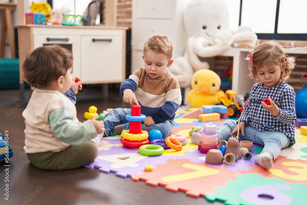Naklejka premium Group of kids playing with hoops toys sitting on floor at kindergarten