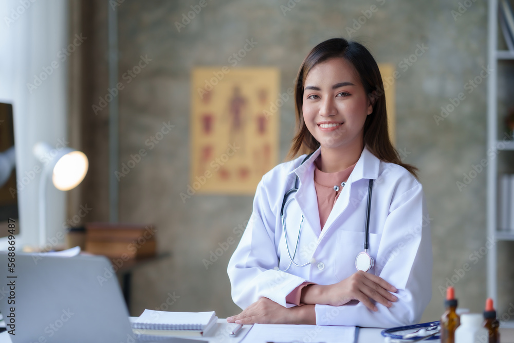 Attractive Asian female doctor checking work on desk, medicines and patient papers and using laptop computer in office room. Attractive Asian female doctor checking work on desk, medicines and patient papers and using laptop computer in office room.
