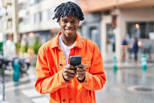African american man smiling confident using smartphone at street