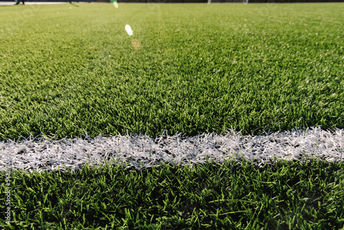 Detailed green soccer field grass lawn texture. White line in centre. Close-up of artificial surface photo
