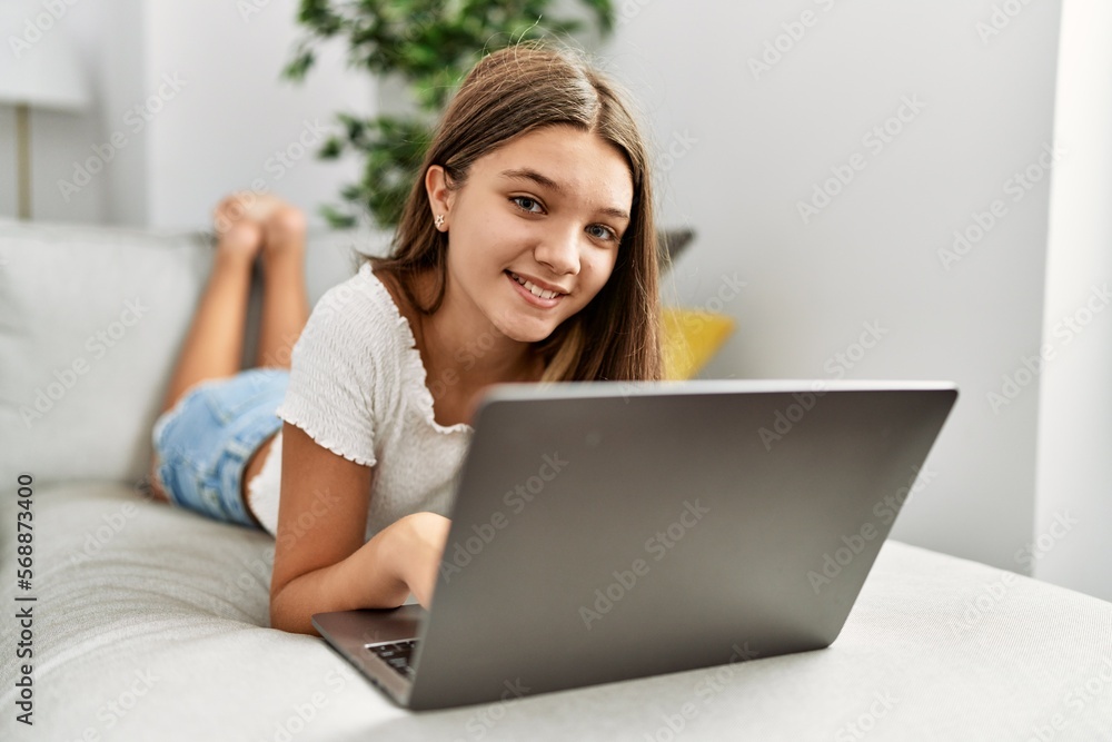 Adorable girl using laptop lying on sofa at home Adorable girl using laptop lying on sofa at home