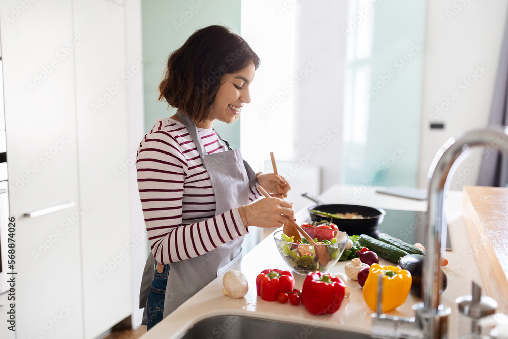 Smiling young arab woman housewife preparing dinner at home